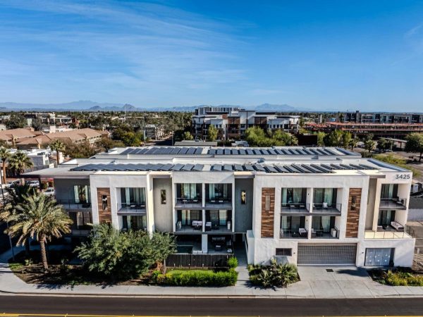 Modern white apartment building with multiple balconies, palm trees along the sidewalk, and solar panels on the roof under a bright blue sky with distant mountains. Address number 3425 visible on the facade.]','A contemporary residential complex with glass-front balconies, landscaped greenery, and a wide street in front, set against a clear desert sky.